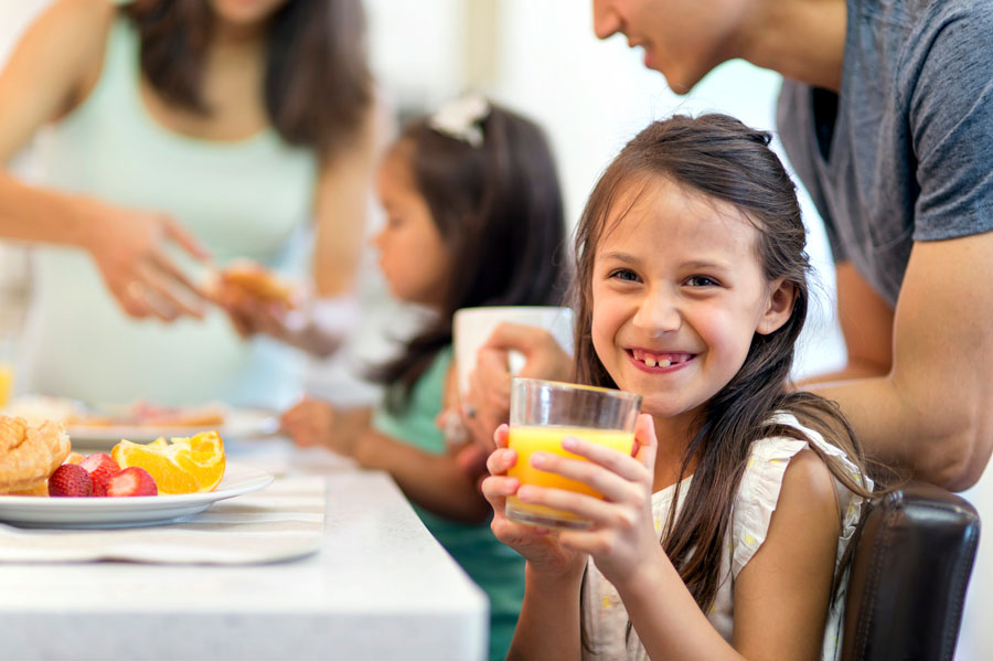 Nena somrient i bevent un suc de taronja