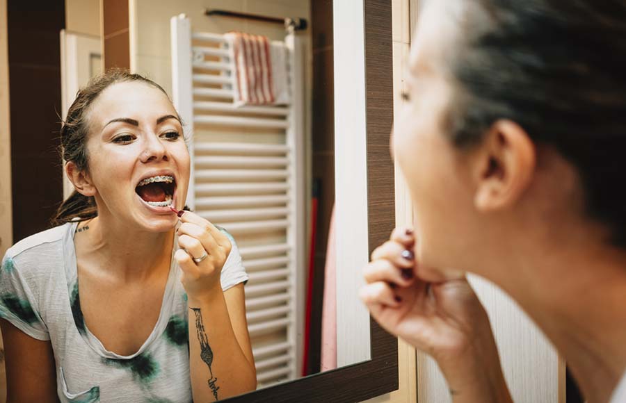 Dona netejant-se les dents amb un raspall interdental al bany